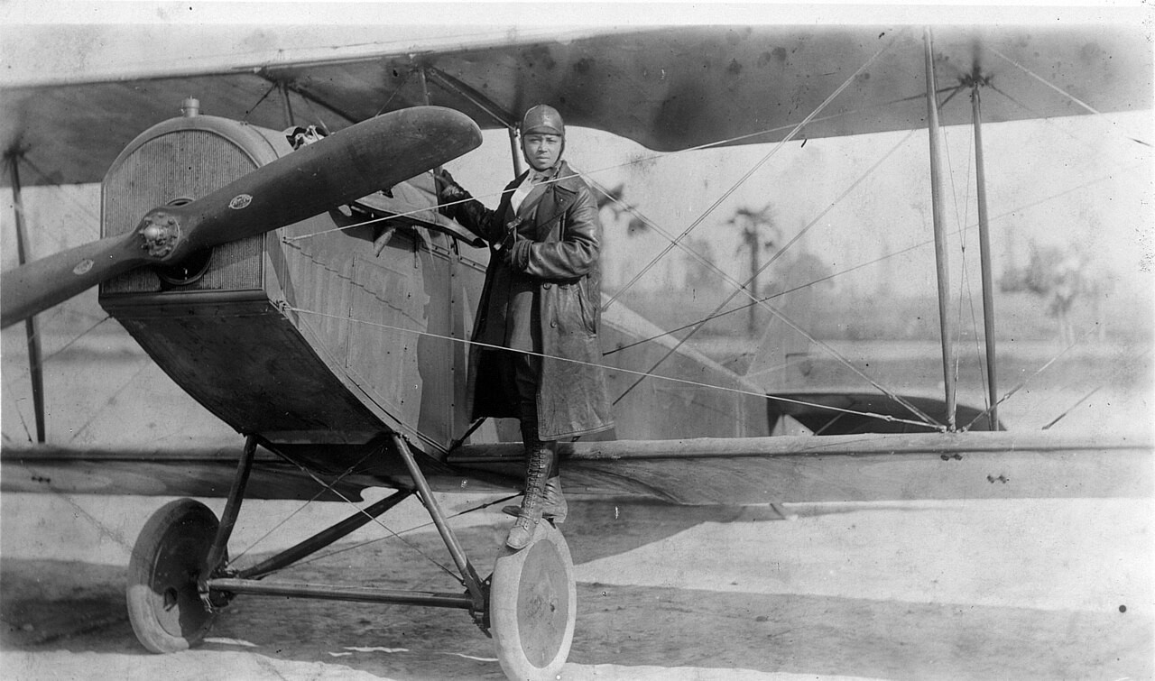 Bessie Coleman stands with an aircraft in 1922